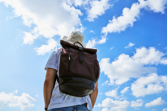 Rear View of Male Traveler with Backpack Looking at Blue Sky