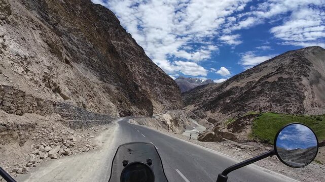 Zanskar, India : Point of view footage of motorcyclist ride passes car on riverside mountain road from Padum to Darcha in Zanskar valley in the Himalayas mountain in Ladakh, India on sunny day
