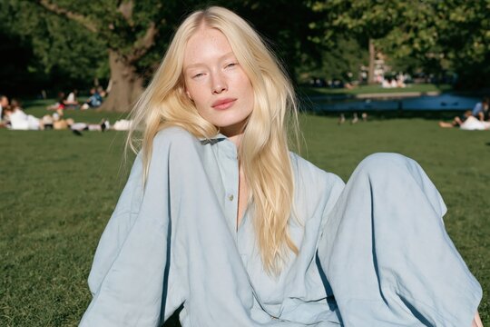 Blonde woman relaxed portrait in a sunlit park for lifestyle background, summer leisure banner and editorial use