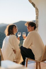 Naklejka premium Romantic sunset terrace scene with couple toasting wine glasses for lifestyle background and cozy travel banner design