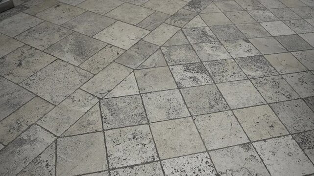 Weathered stone tile plaza with subtle shifting daylight and emphasized grout texture, with stone, tile, pavement, floor detail, showing ground, plaza, courtyard, pattern context