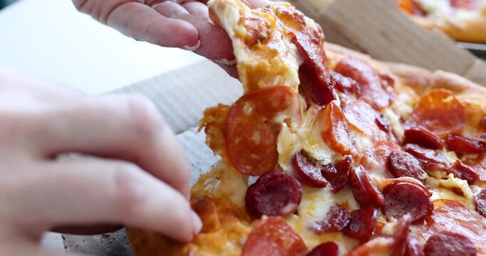 Cheesy slices of pizza are being pulled apart in a cozy kitchen. The warm aroma fills the air as each piece reveals layers of pepperoni and melted cheese.