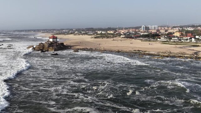Capela do Senhor da Pedra on the sandy coast of Porto during a sunny afternoon