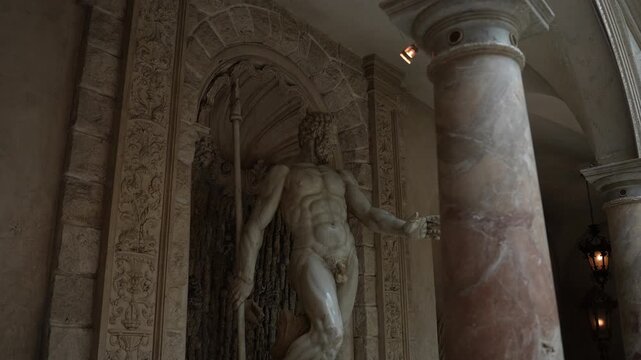 Classical marble statue in ornate carved niche beside polished column under warm lantern light, with statue, marble, sculpture, male detail, showing muscular, classical, contrapposto, niche context