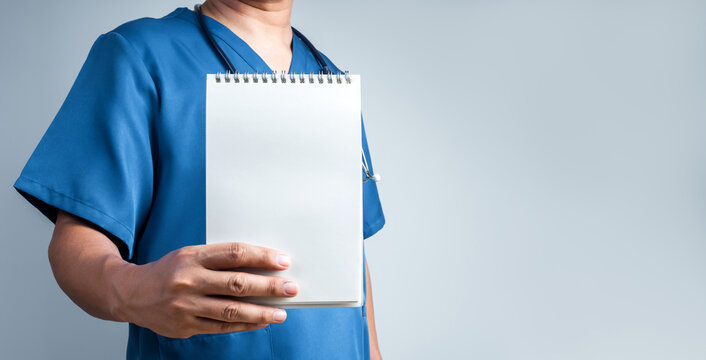 Healthcare professional in scrubs presents blank notepad template with copy space for personalized patient care plan, to do list, treatment guidance, medical checklist or health consultation concept.