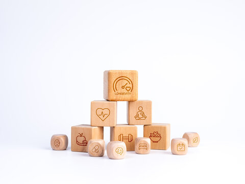 Wooden blocks with fitness, nutrition, sleep, mindfulness, heart health and planning icons form a holistic longevity framework, illustrating preventive wellness and healthy aging strategy concept.