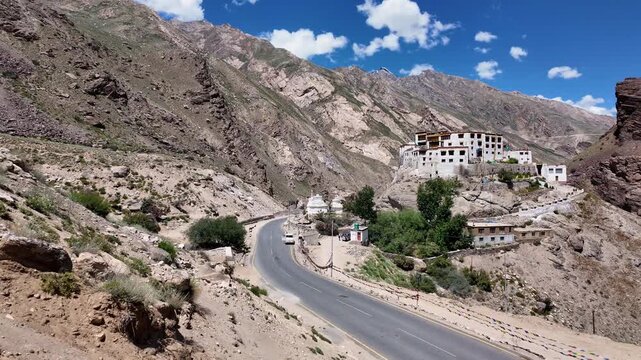 Zanskar, India : Elevated panoramic footage of of mountain road by Bardan Gompa, Buddhist monastery on rocky outcrop in near Padum of Zanskar valley in Ladakh, India on sunny day