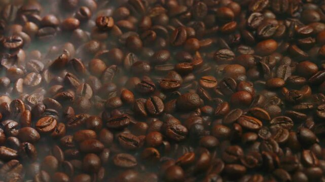 Slow cinematic dolly shot gliding over hot, freshly roasted coffee beans with aromatic steam rising from the surface, creating a warm, rich and mouthwatering coffee atmosphere.
