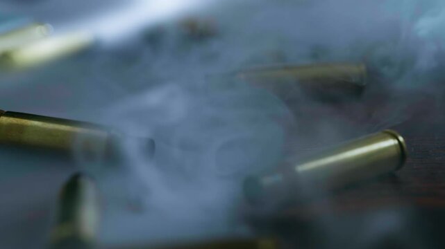 Close-up of rifle and pistol ammunition falling onto a surface amid cinematic smoke, conveying danger, military power, war and the destructive nature of armed conflict.