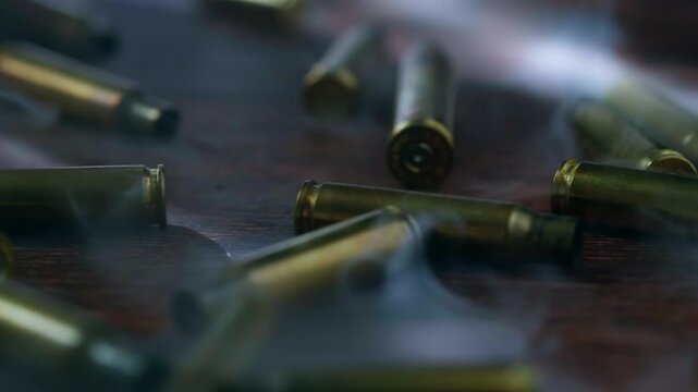 Falling rifle and handgun bullets surrounded by drifting smoke, creating a dramatic cinematic image evoking war, armed conflict, violence, danger and military tension.
