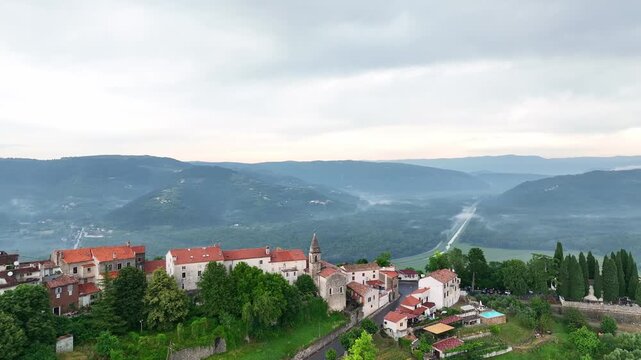 Cinematic drone footage of Motovun medieval town on hilltop in Istria Croatia during early summer with stone houses, green valley, vineyards and authentic European heritage landscape