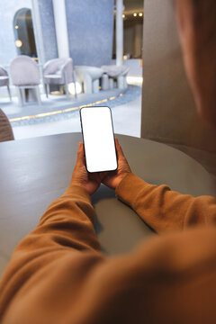 Vertical mockup image of a woman holding mobile phone with blank desktop screen in cafe
