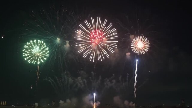 Colorful fireworks display exploding in dark night sky over city skyline