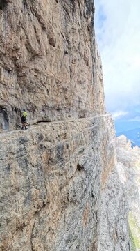 Hiker Hiking along Narrow Rock Ledge on Via Ferrata delle Bocchette Centrali in Brenta Dolomites