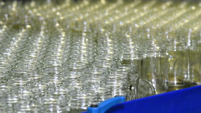 A conveyor belt with neat rows of glass jars