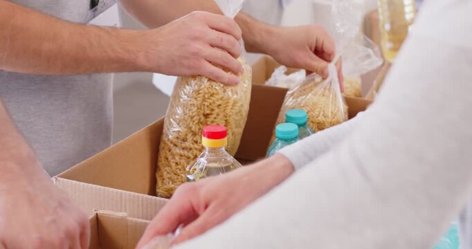 Food bank table, stocks of meal, volunteer group distribute basic provisions, working in charitable foundation, collect donation to needy, separating donations stuff, bottled water for people in need