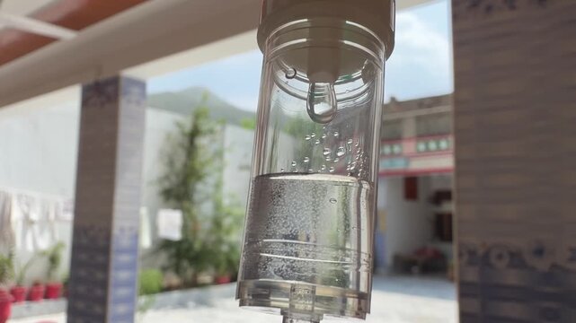 A clear chamber showing controlled drip flow, filtration, and air‑fluid separation within a standard IV infusion set.