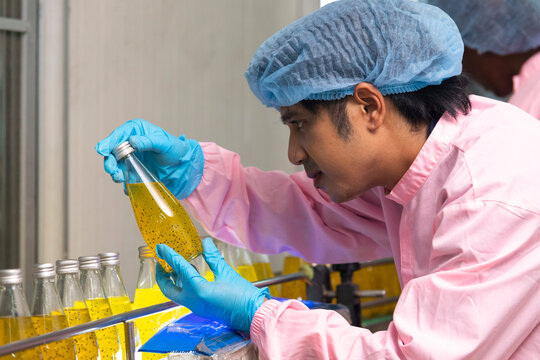 Two factory workers monitoring cold drink bottles on production line at drinks production plant.