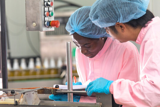 Two factory workers monitoring cold drink bottles on production line at drinks production plant.