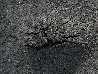 Close up top down view of dark cracked asphalt texture showing road damage and urban decay © Oleksandra