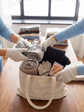 Winter clothing donation volunteers packing blankets gloves scarves community support hands fill a reusable bag with warm blankets scarves for winter relief campaigns and clothing donation outreach
