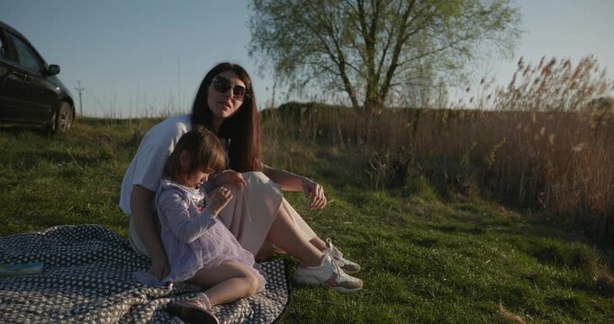 Family rest near Lake. Young mother spend time with children son and daughter enjoying nature. 4K 10-bit