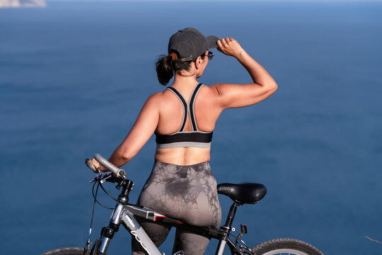 Cyclist bicycle athlete standing with mountain bike looking at ocean view enjoying freedom during outdoor fitness training and exercise