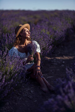 Woman lavender field enjoying summer sunset light holding fresh flower bouquet