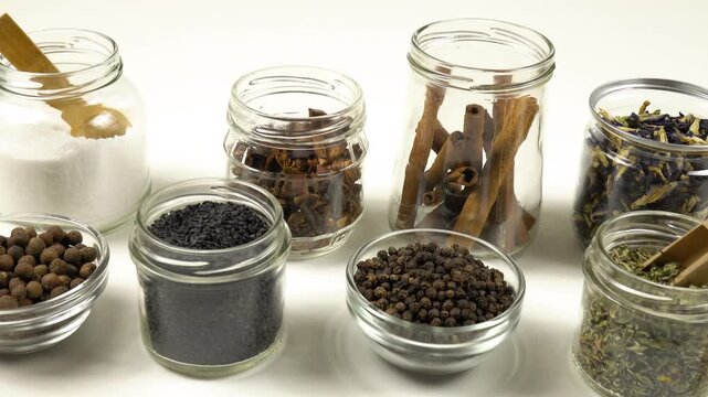 Different shapes and sizes of empty glass jars filled spice and herb for storage stand on a white table, side view, Reuse of glass jars, kitchen organization