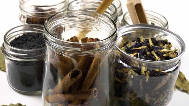 Different shapes and sizes of empty glass jars filled spice and herb for storage stand on a white table, side view, Reuse of glass jars, kitchen organization