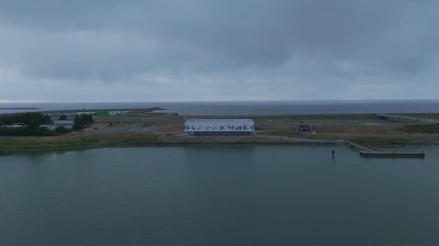 Aerial drone footage slowly flying backward from a modern visitor center on the Afsluitdijk in the Netherlands. 