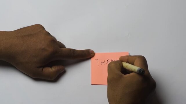 Hand Writing Thank You on Peach Sticky Note with Happy Face