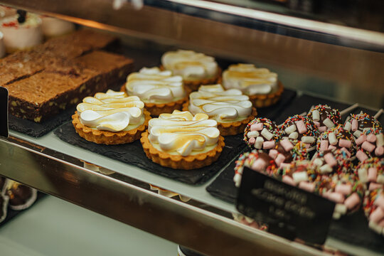 Bakery display filled with toasted meringue tarts, brownies, and chocolate treats topped with marshmallows and colorful sprinkles