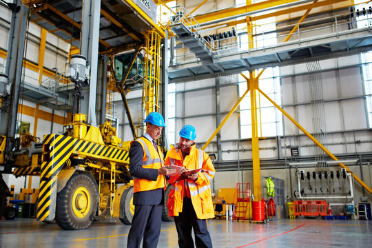 Tablet, team and talk with clipboard in warehouse for shipping, logistics service or safety checklist. Men, supply chain or planning online at depot for crane, compliance or transport tracking app