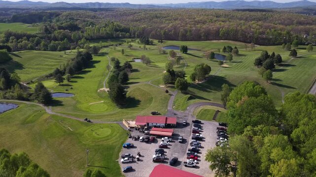 High aerial drone shot tilting down to show overhead angle of large countryside golf course in West Virginia