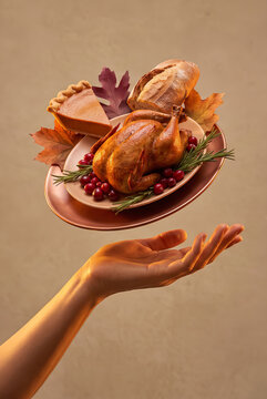 Hand holding a floating Thanksgiving plate of turkey and pie