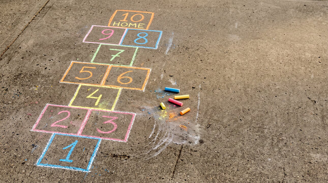 Colorful hopscotch grid drawn with chalk on pavement, classic outdoor childhood game with numbered squares, playful summer activity and nostalgic schoolyard concept