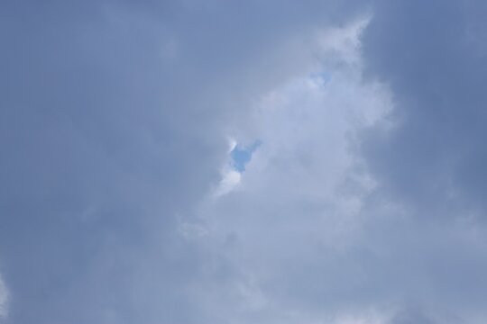 Small patch of blue sky breaking through misty grey storm clouds