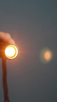 Hand holding a small flashlight with a warm orange glow, illuminating the darkness