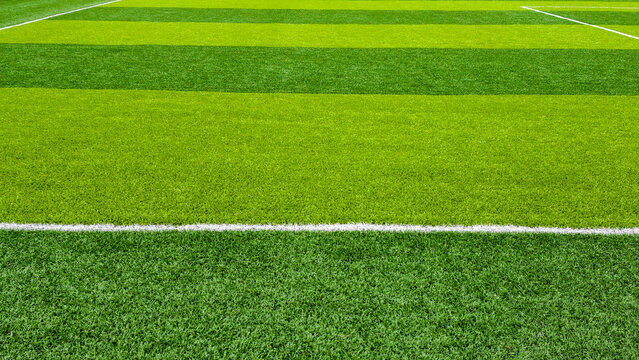 Artificial turf playing field with alternating green strips and crisp white boundary lines, low maintenance synthetic surface ideal for sports, training, recreation, and events