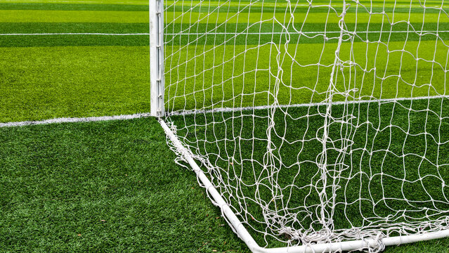 Soccer goal with white net and posts standing on a vibrant green artificial turf field, marking the scoring area during a game or practice session
