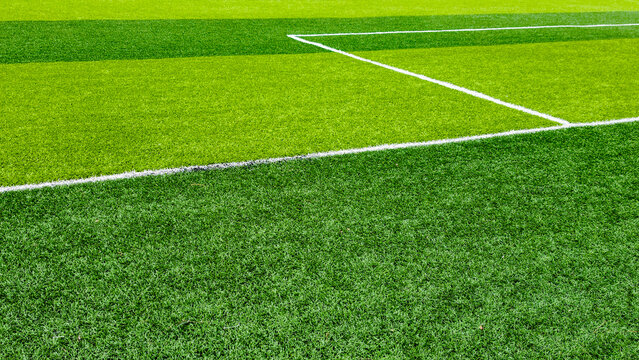 Artificial turf field featuring bright green color segments and white markings, creating a vivid background for team sports, training, and competition
