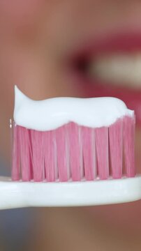 Close-up of pink toothbrush with white toothpaste ready for brushing teeth