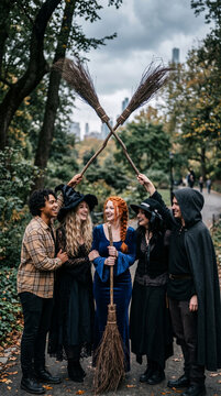 Group of people in costumes with brooms, representing Halloween, fantasy, or a themed event