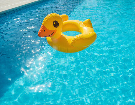 A yellow duck inflatable floatie floating in the sunny swimming pool water, representing a summer vacation and child swimming pool activities concept.