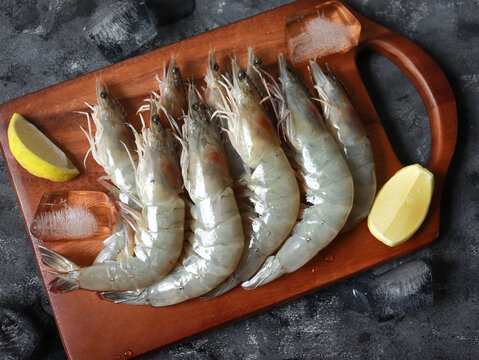 Fresh raw white prawns on wooden cutting board. Sustainable food.