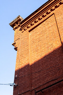 Angle view of historic red brick building facade against clear blue sky in bright sunlight