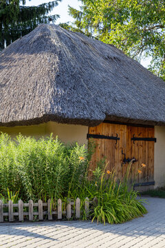 Traditional rural barn with thatched roof double wooden doors and blooming flowers