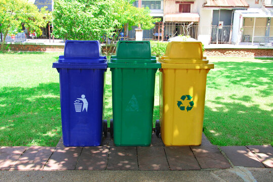 Three colorful recycling trash bins placed in a public park