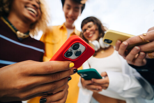 Friends using smartphones together, sharing social moments